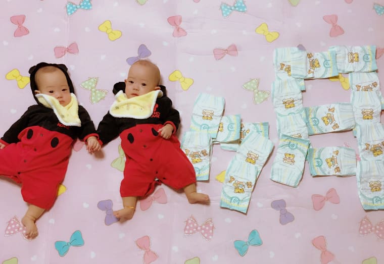 手をつないで寝転がる11か月の双子の赤ちゃんたち